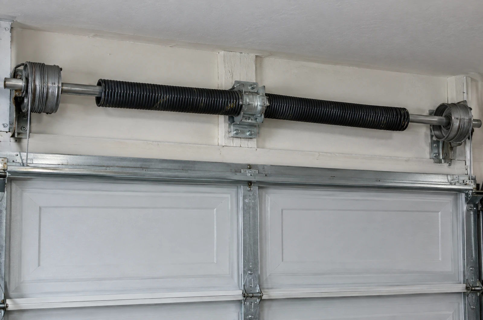 Torsion springs on the steel shaft above a closed garage door